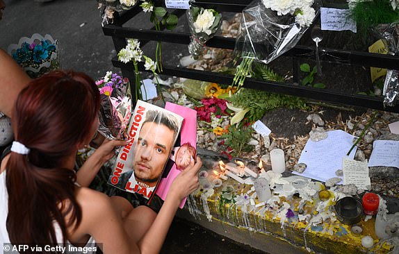 A fan holds a magazine with a photo of British singer Liam Payne as she pays tribute to him outside the hotel where he died in Buenos Aires, on October 17, 2024. Tributes poured in Thursday for British singer Liam Payne, a former member of the best-selling boy band One Direction, after he plunged to his death from the balcony of a Buenos Aires hotel. (Photo by Luis ROBAYO / AFP) (Photo by LUIS ROBAYO/AFP via Getty Images)